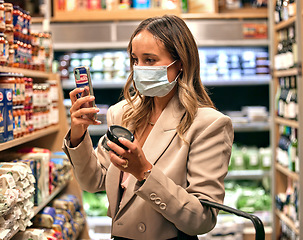 Image showing Supermarket, shopping and covid customer with face mask for grocery, food or product price, inflation or discount check. Covid 19, retail and woman choice, decision or thinking of groceries budget