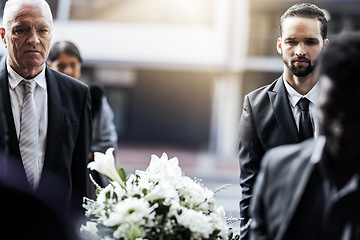 Image showing Man, funeral and carrying coffin in grief for loss, death or sorrow walking to the cemetery or burial. Group of mourning men lifting casket together of the deceased for ceremony, church or graveyard