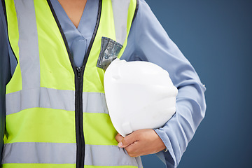 Image showing Closeup, construction worker and helmet with vest for safety in studio with blue background. Woman, builder and construction industry with gear, clothes and hardhat for health, wellness or protection