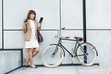 Image showing Business woman, phone and coffee with bicycle for eco friendly transport for travel on city break while online with 5g network. Entrepreneur on break using mobile app for communication and networking