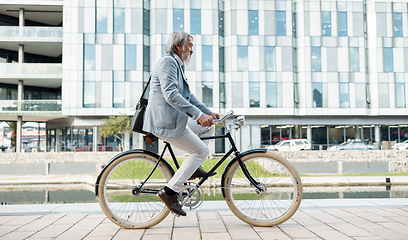 Image showing Travel, city and Asian businessman on bicycle, cycling to work in urban town for low carbon footprint. Sustainability, transport and senior man riding bike to workplace for eco friendly commute