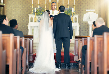 Image showing Wedding, priest and couple at the altar for marriage vows in commitment ceremony in a church from behind. Married, love and caring bride and groom celebrating their loving relationship in a chapel