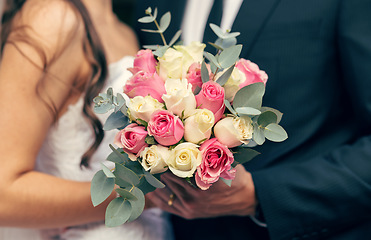 Image showing Flowers, wedding and love with a bouquet in the hands of a bride and groom on their marriage day closeup. Rose, married and celebration event with a floral arrangement in hand during a ceremony