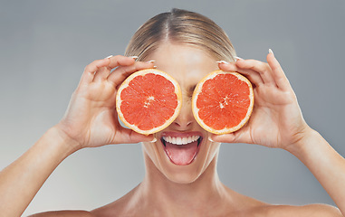 Image showing Woman, hands and fruit eyes in skincare holding grapefruit for healthy wellness against a grey studio background. Happy female in beauty cosmetics with juicy or fruity smile for vitamin C nutrition