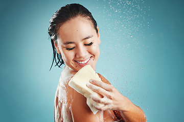 Image showing Studio, skincare and woman in shower with sponge isolated on a blue background mockup. Water splash, cleaning or healthy hygiene of female model bathing, washing or showering for beauty and body care