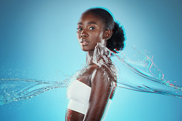 Image showing Skincare, water and black woman with a splash for hydration, cleaning and beauty against a blue studio background. Spa, wellness and African model with peace, calm and relax from liquid bodycare