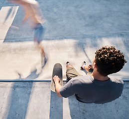 Image showing Skate park, top view and man with a skateboard in the city street for fun or sports training. Skating, fitness and young male skater sitting on a ramp before practicing to skate in an urban town.