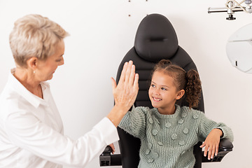 Image showing High five, optometrist and children with a girl and woman in an optometry appointment for prescription lenses. Motivation, eye test and success with a female child and optician in celebration