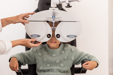 Image showing Girl, Ophthalmologist and eye test in an exam in clinic for medical check. Female optician or optometrist expert checking vision of a child examination equipment inside an optometry room at hospital