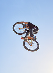 Image showing Mountain bike, speed and sports with a man jumping in the air during a race outdoor against the sky from below. Blue sky, energy and bicycle with a professional male biker or athlete in action