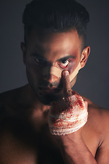 Image showing Blood, boxing injury and man with bruise from fight conflict, criminal violence or dark crime with middle finger emoji sign. Shadow, rebel lifestyle and portrait of mma boxer with first aid bandage