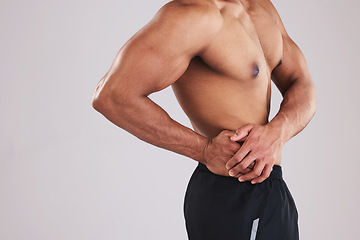 Image showing Pain, waist and man with an injury after exercise, fitness and training against a grey studio background. Healthcare, accident and person feeling their body with appendicitis and medical emergency