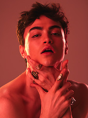 Image showing Beauty, cosmetics and man in studio with red lighting to model with jewellery, makeup and designer rings. Creative art, lgbt and portrait of young male pose for skincare, beauty products and fashion