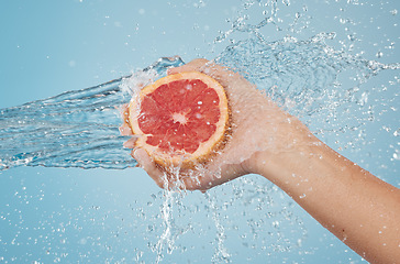 Image showing Fruit, water and hand splash for beauty, care and healthy skincare and bodycare on a blue studio background. Grapefruit, hands and hygiene with vitamin c for organic and natural body skin cleansing