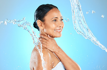 Image showing Mature woman, wet or water splash on blue background in studio skincare wellness, hygiene maintenance or body cleaning. Smile, happy or beauty model with pouring liquid healthcare or hydration motion