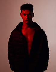 Image showing Portrait, fashion and style with a man model in studio on a wall background with red light for contemporary clothes. Beauty, confidence and edgy with a handsome young male posing for trendy clothing