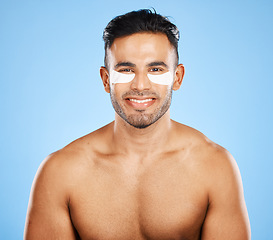 Image showing Beauty, skincare and eye patch with grooming and man in wellness for skin portrait against blue studio background. Eye care, healthy face and fresh glow with smile, clean with hygiene and cosmetic.