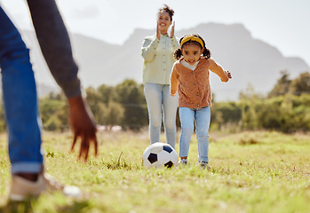 Image showing Parents, park and girl kick soccer ball for fun sports learning, bonding and relax in sunshine, garden and nature together. Happy family, little girl and black people playing football on grass field