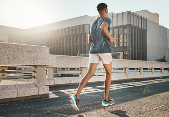 Image showing Running, fitness and city man for body training, workout and exercise with motivation, goal and energy in morning sun. Young sports, athlete or runner person run in urban street or bridge for health