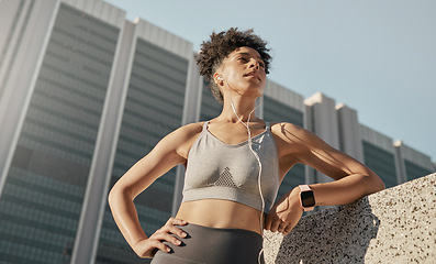 Image showing Black woman, city fitness and music earphones for sports motivation, exercise and workout in urban town from below. Focus, strong and healthy athlete listening to audio outdoors for wellness training