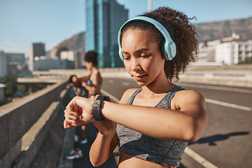 Image showing Smartwatch, headphones and fitness black woman in city with running results, workout progress check and goals. Young runner or sports girl with smart watch and music tech for outdoor training app