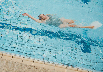 Image showing Senior woman, swimming pool and happy retirement, healthy lifestyle or wellness sport in summer outdoor. Old woman doing backstroke in water for activity, hobby and relax on holiday, vacation and sun