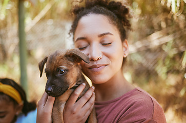 Image showing Love, dog and animal shelter with a black woman hugging a foster pet while at a shelter to adopt a rescue animal. Volunteer, charity and adoption with a female holding a cute puppy at the pound