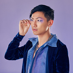 Image showing Punk, rock or gay man with eyeshadow, makeup and cosmetics, vintage or retro fashion clothes on a purple background for pop art style. Asian lgbtq identity model in studio for creative color mockup