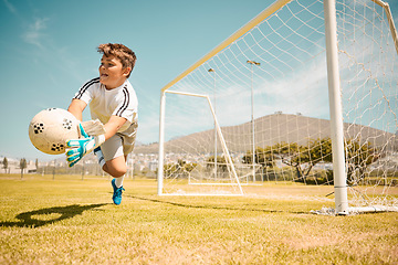 Image showing Football, boy goalkeeper and jump, saving ball from goals at outdoor sports field. Soccer, kid and competition game with fitness, goal keeper and soccer ball on grass, success and action to save goal
