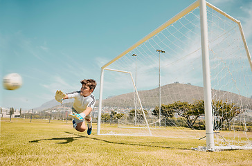 Image showing Soccer, sports and children with a goalkeeper saving a shot during a competitive game on a grass pitch or field. Football, kids and goal with a male child diving to save or stop a ball from scoring