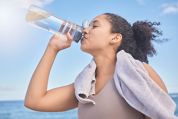 Image showing Water, fitness and woman with a drink after exercise, workout or training by the sea. Sports, motivation and energy from a runner with a bottle for hydration after running by the beach in nature