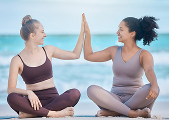 Image showing Woman, friends and high five in yoga at the beach for spiritual training or wellness exercise on the sand. Happy women relaxing touching hands in success for healthy zen or lifestyle balance together