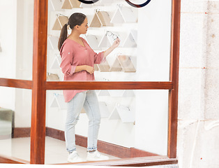 Image showing Shopping, retail and woman with glasses at a store for quality choices, frames on promotion and eye care. Decision, girl or customer checking options for better eyesight or clear vision at optician