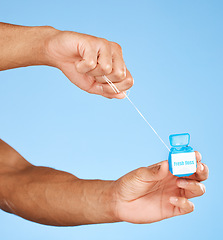 Image showing Floss, dental healthcare and man hands with product container on studio mock up for teeth, mouth and dentist cleaning marketing. Medical, wellness and dental floss health care with blue mockup