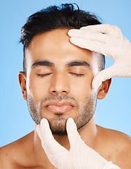 Image showing Plastic surgery, man and cosmetics for face, skincare or natural beauty against blue studio background. Young male, white gloves or organic facial for smooth, glow skin and hydration for rejuvenation