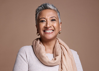 Image showing Face, fashion and beauty with a senior woman in studio on a brown background to promote contemporary style. Portait, fashionable and trendy with a mature female posing to model a clothes brand