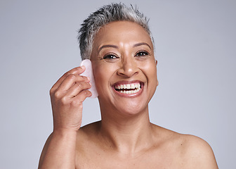 Image showing Beauty, gua sha and skincare of a senior woman in studio for dermatology, cosmetics and facial massage on a grey background. Face portrait of a mature model happy about skin results with rose quartz