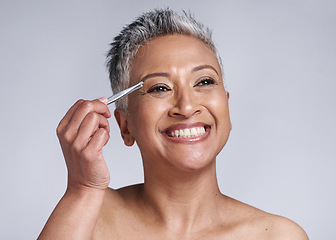 Image showing Beauty, eyebrow and hair removal of a senior woman in studio for skincare, cosmetics and makeup with a smile, happiness and glow. Mature model with tweezers for removing facial hair for clear skin
