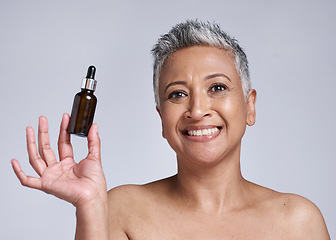 Image showing Senior woman, serum and skincare with smile for natural beauty, organic facial and wellness in grey studio background. Body care, model and with cosmetic oil for smooth skin, glow or happy to hydrate