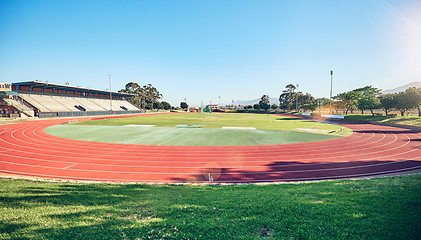 Image showing Sport, fitness and stadium track for running, outdoor and exercise landscape, blue sky and grass. Active, workout motivation and run for healthy life and sports view sun flare with cardio.