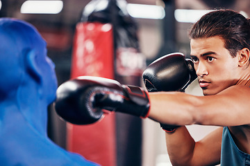 Image showing Fitness, boxing and man at gym for exercise, training and workout with a dummy for fast, speed and agile punch for sports match or competition. Focus, face and boxing gloves on athlete boxer to fight