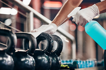 Image showing Kettlebell, cleaning service and hands cleaning at a gym with liquid soap in spray bottle with cloth in gloves. Janitor or cleaner wipes dirty bacteria on dusty weights or fitness training equipment