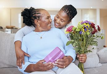 Image showing Black woman, mothers day and hug with flowers on sofa for love, box or gift to mom in home. Woman, bouquet and senior mama with wow, smile or happy for surprise, celebration or birthday on couch