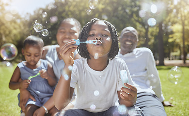 Image showing Happy, nature and black family blowing bubbles while playing, bonding and enjoying summer in the park. Happiness, father and mother with children having fun together in a green garden in South Africa