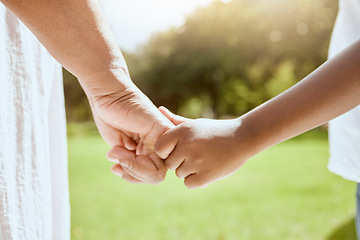 Image showing Park, family and parent holding hands with child bonding together enjoying nature and outdoors. Summer, love and hands of young kid with adult bonding, carefree on weekend, holiday and vacation