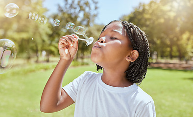 Image showing Park, child and black girl blowing bubbles enjoying fun time alone outdoors, joy and childhood development. Happy, freedom and kid learning and playing with soap bubble toy or wand and relax on grass