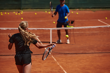 Image showing A professional tennis player and her coach training on a sunny day at the tennis court. Training and preparation of a professional tennis player