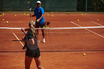 Image showing A professional tennis player and her coach training on a sunny day at the tennis court. Training and preparation of a professional tennis player