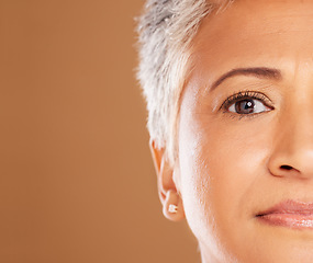 Image showing Skincare, makeup and half face of a senior woman for beauty, wellness and body cosmetics against a brown mockup studio background. Luxury, retirement and portrait of an elderly model with space