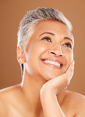 Image showing Face, beauty and thinking with a senior woman in studio on a brown background for wellness or natural skincare. Idea, cosmetics or skincare with a mature female posing to promote an antiaging product
